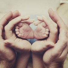 Ножки малыша в руках родителей