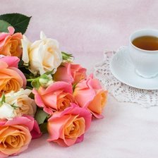 Красивый букет роз на столе с чашкой  чая